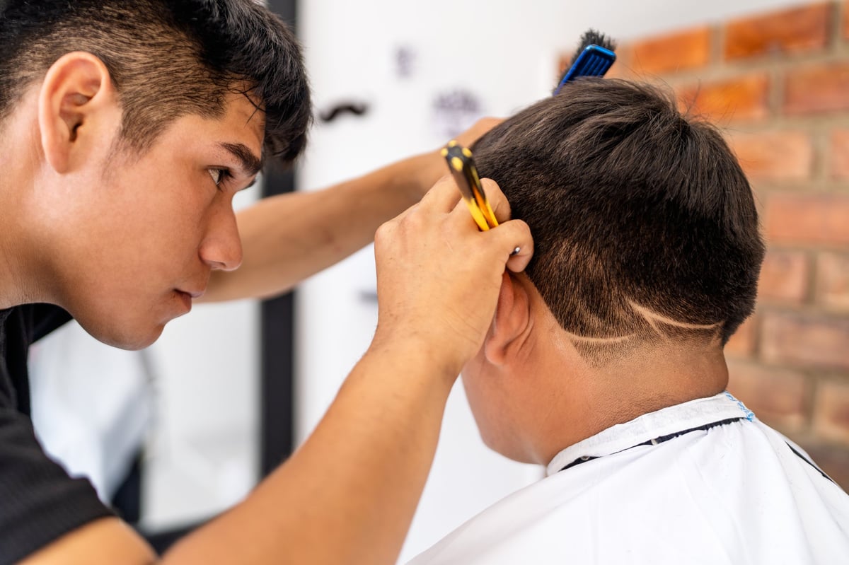 Barber creating a modern design on a younger customer's hair